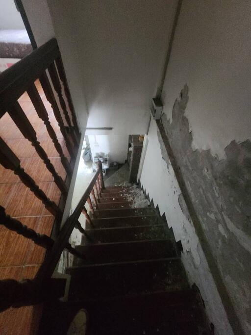 View of staircase leading to lower level with visible damage on walls and steps