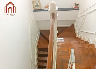 A well-lit staircase with wooden steps and white railing