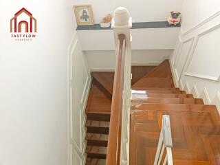 A well-lit staircase with wooden steps and white railing