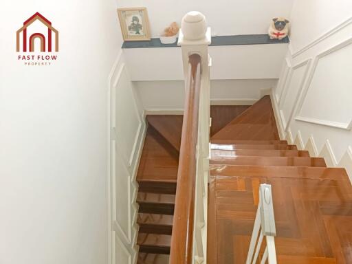 A well-lit staircase with wooden steps and white railing