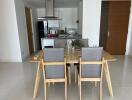 Modern dining area with wooden table and grey chairs adjacent to a kitchen