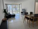 Modern living room with a dining area, black sofa, and large windows providing a city view