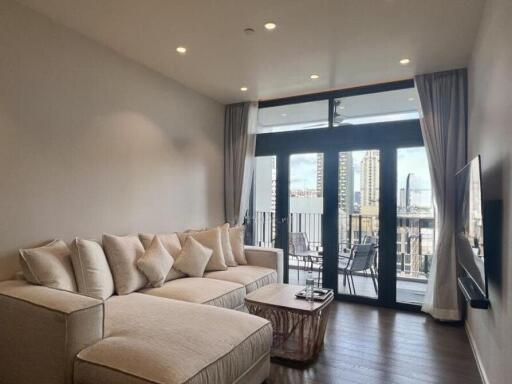 Modern living room with a large beige sectional sofa and balcony access