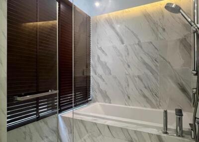 Marble-tiled bathroom with bathtub and showerhead