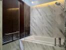 Marble-tiled bathroom with bathtub and showerhead