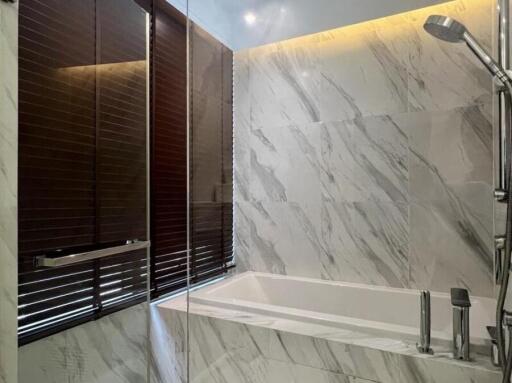 Marble-tiled bathroom with bathtub and showerhead