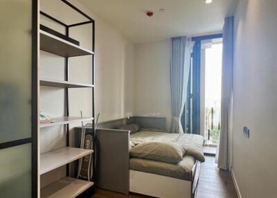 Small bedroom with shelves and bed near a window