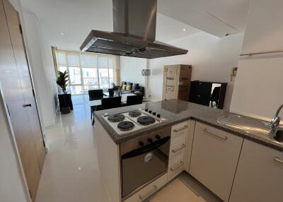 Modern kitchen with granite countertops and open living area in background