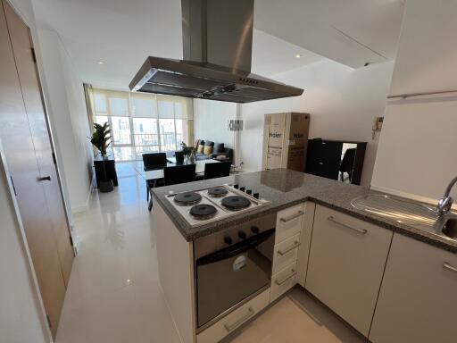 Modern kitchen with granite countertops and open living area in background