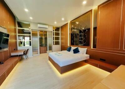 A modern, spacious bedroom with a large bed, built-in furniture, and warm lighting