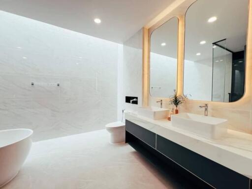 Modern bathroom with double sink vanity, freestanding bathtub, and large mirror