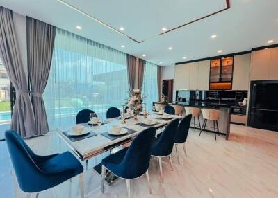 Modern dining area and kitchen with large windows and pool view