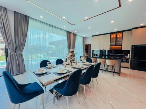 Modern dining area and kitchen with large windows and pool view