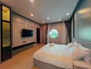 Modern spacious bedroom with large bed and circular window