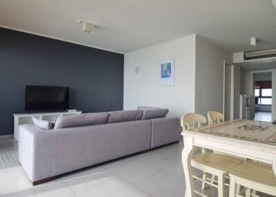 Living room with a sofa, TV, dining table, and large windows