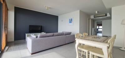 Living room with a sofa, TV, dining table, and large windows