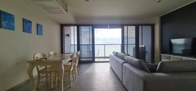 Spacious living room with a dining area, large windows, and balcony view