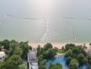 Aerial view of beachfront, swimming pools, and landscaped gardens