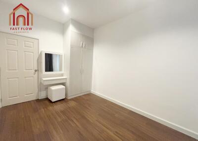 Bedroom with white walls, wooden floor, and minimal furniture