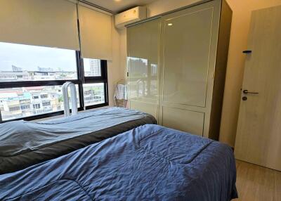 A bedroom with twin beds, large windows, and a wardrobe