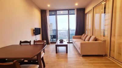 Modern designed living room with a sofa, dining table, wall-mounted TV, and a balcony with a city view.