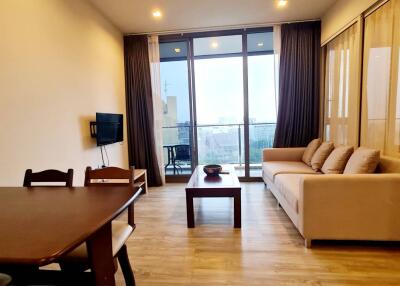 Living room with a dining area, sofa, coffee table, wall-mounted TV, and a balcony view