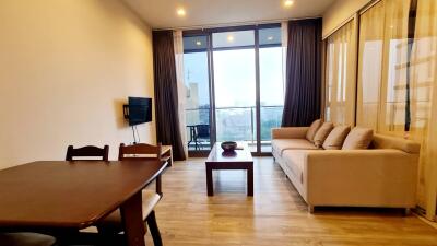 Living room with a dining area, sofa, coffee table, wall-mounted TV, and a balcony view