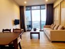 Living room with a dining area, sofa, coffee table, wall-mounted TV, and a balcony view