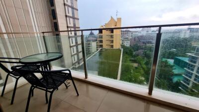 A balcony with a table and two chairs overlooking a city view