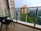 A balcony with a table and two chairs overlooking a city view