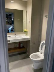 Modern bathroom with large mirror, sink, and toilet