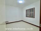 A vacant bedroom with tiled flooring and barred windows