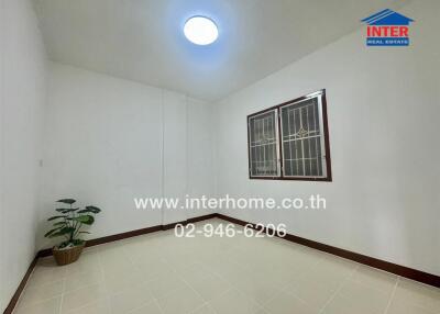 Empty bedroom with window, tiled floor, and a plant