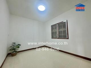 Empty bedroom with window, tiled floor, and a plant