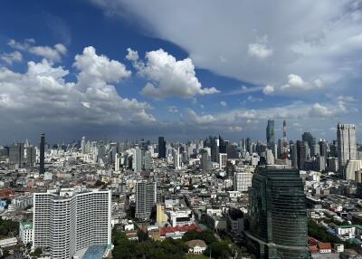 Aerial view of city skyline with high-rise buildings and cloudy blue sky