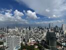 Aerial view of city skyline with high-rise buildings and cloudy blue sky