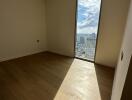 Empty room with wooden flooring and large window