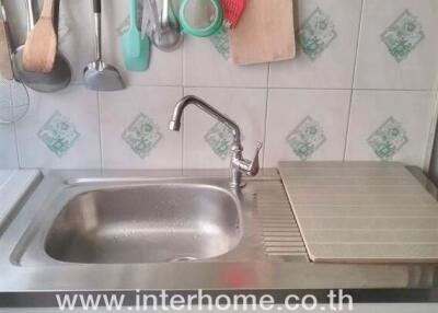 Kitchen sink area with utensils hanging above