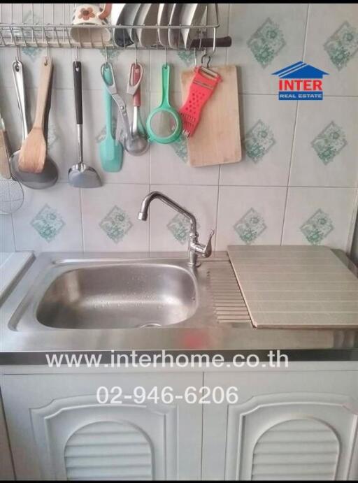 Kitchen sink area with utensils hanging above