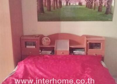 Bedroom with pink bedspread and wall poster