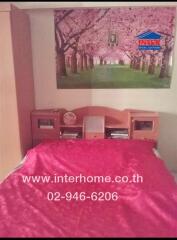 Bedroom with pink bedspread and wall poster