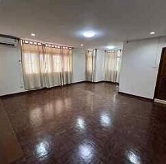 Spacious living room with wooden flooring and large windows with curtains