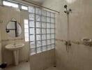 Spacious bathroom with shower, sink, and glass block partition