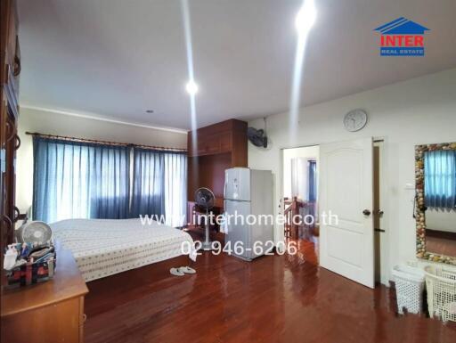 Spacious bedroom with wooden floors, large bed, and modern amenities