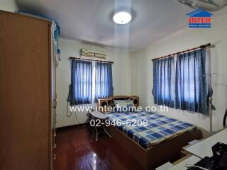 Bedroom with bed, shelves, and windows with blue curtains