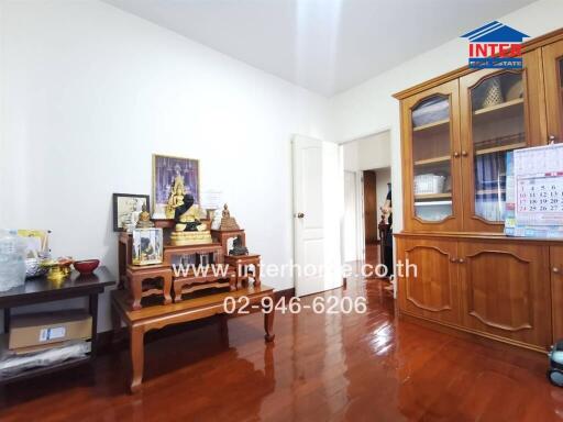 Well-lit living room with a wooden floor and a decorative cabinet