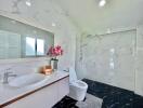 Modern bathroom with marble walls and black floor, featuring a walk-in shower and sink with mirror