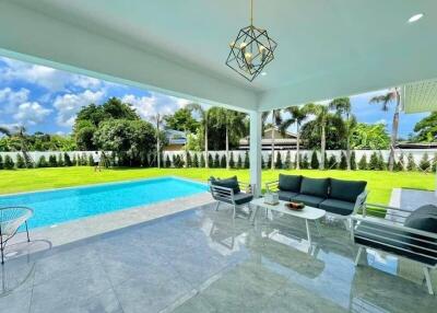 Covered outdoor seating area facing a pool and backyard