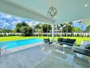 Covered outdoor seating area facing a pool and backyard