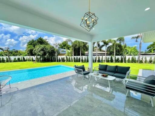 Covered outdoor seating area facing a pool and backyard